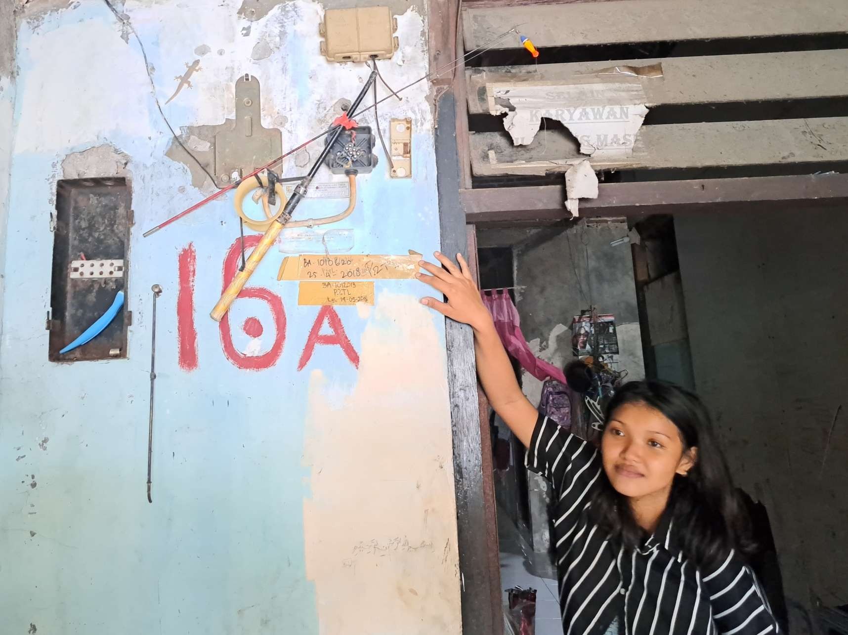 Ayu Aura saat menunjukkan listrik di rumahnya yang dicabut PLN sejak 2018. (Foto: Pita Sari/Ngopibareng.id)