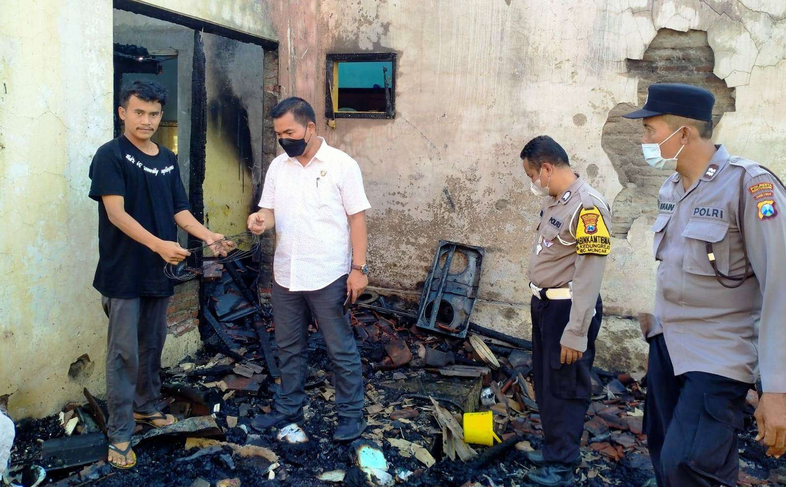 Petugas  Polsek Muncar sedang melakukan olah TKP di rumah yang terbakar (foto: istimewa)