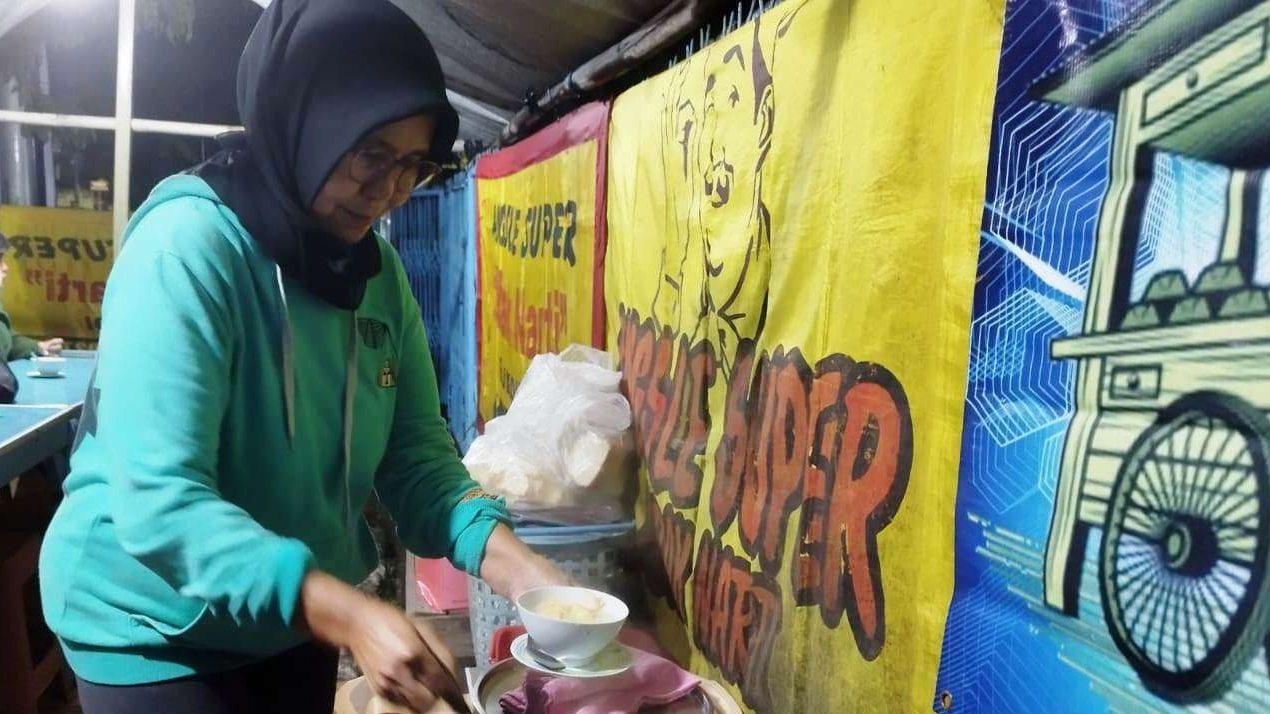 Sunarti sedang menyiapkan angsle untuk disajikan kepada pengunjung warungnya. (Foto: Muh. Hujaini/Ngopibareng.id)