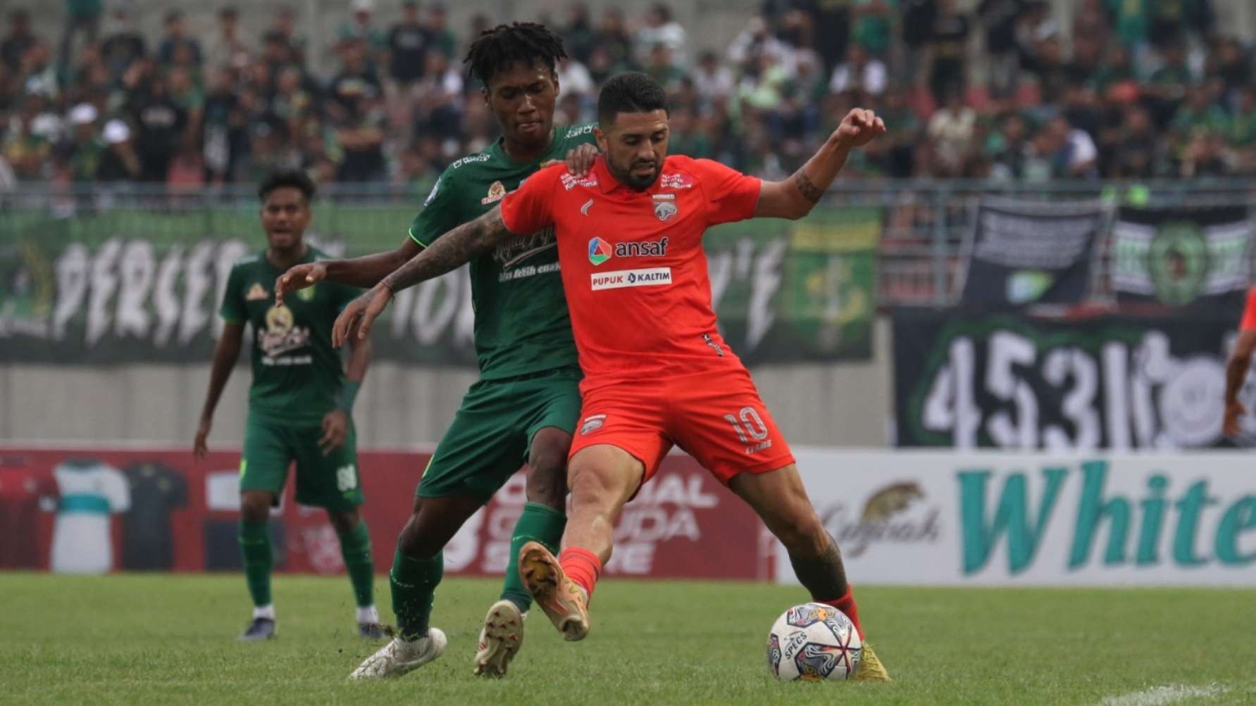 Pemain Borneo FC, Jonathan Bustos (oranye) mendapat pengawalan ketat dari Pemain Persebaya Alta Ballah di Stadion Gelora Joko Samudro, Gresik, Jumat 3 Februari 2023. (Foto: Fariz Yarbo/Ngopibareng.id)