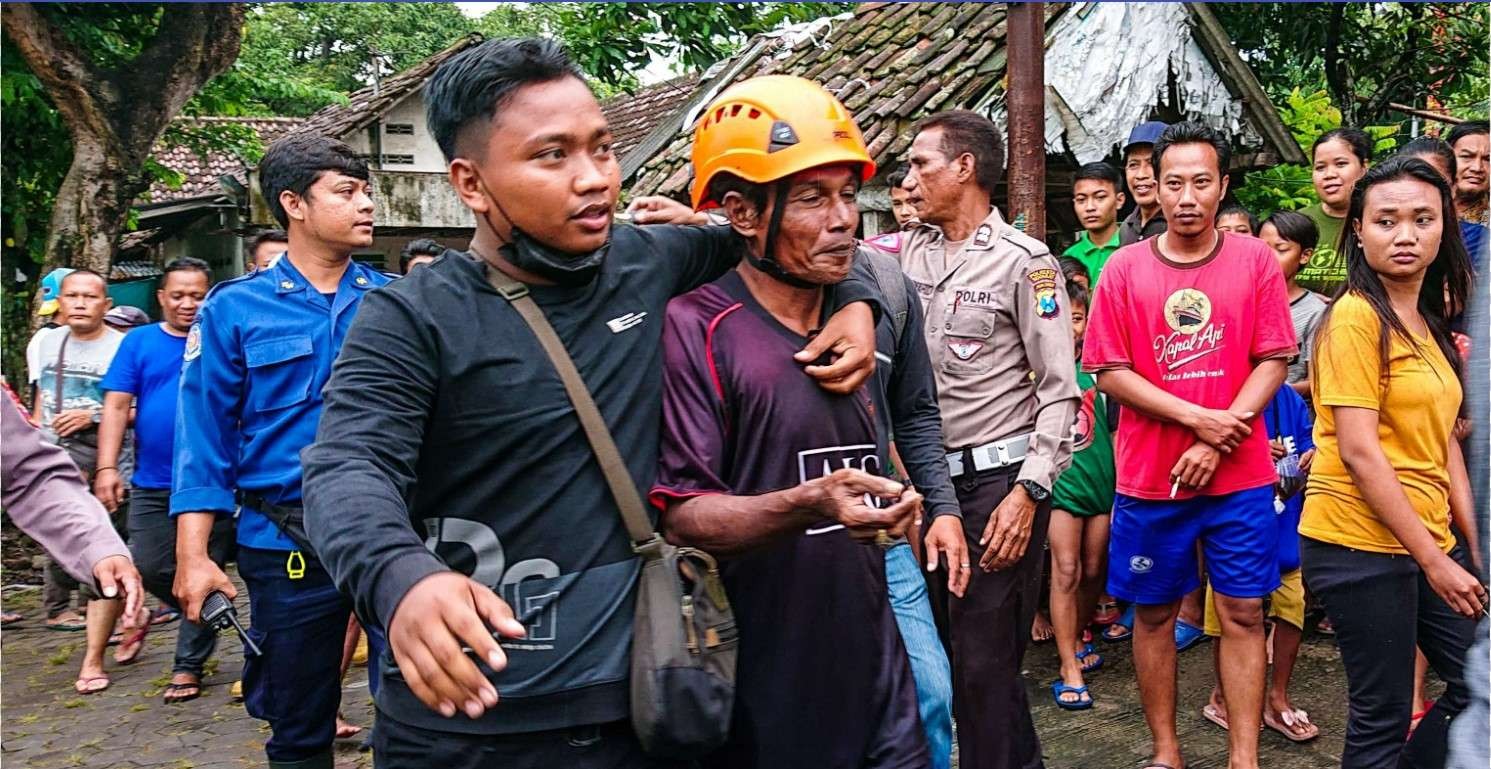 Agus (helm oren) saat berhasil di evakuasi petugas damkar (foto :Aini/Ngopibareng.id)