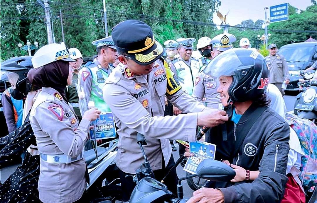 Kapolres Situbondo, AKBP Dwi Sumrahadi didampingi Kasatlantas AKP Anindita membagikan dan memasangkan helm gratis kepada pemotor. (humas polres situbondo)