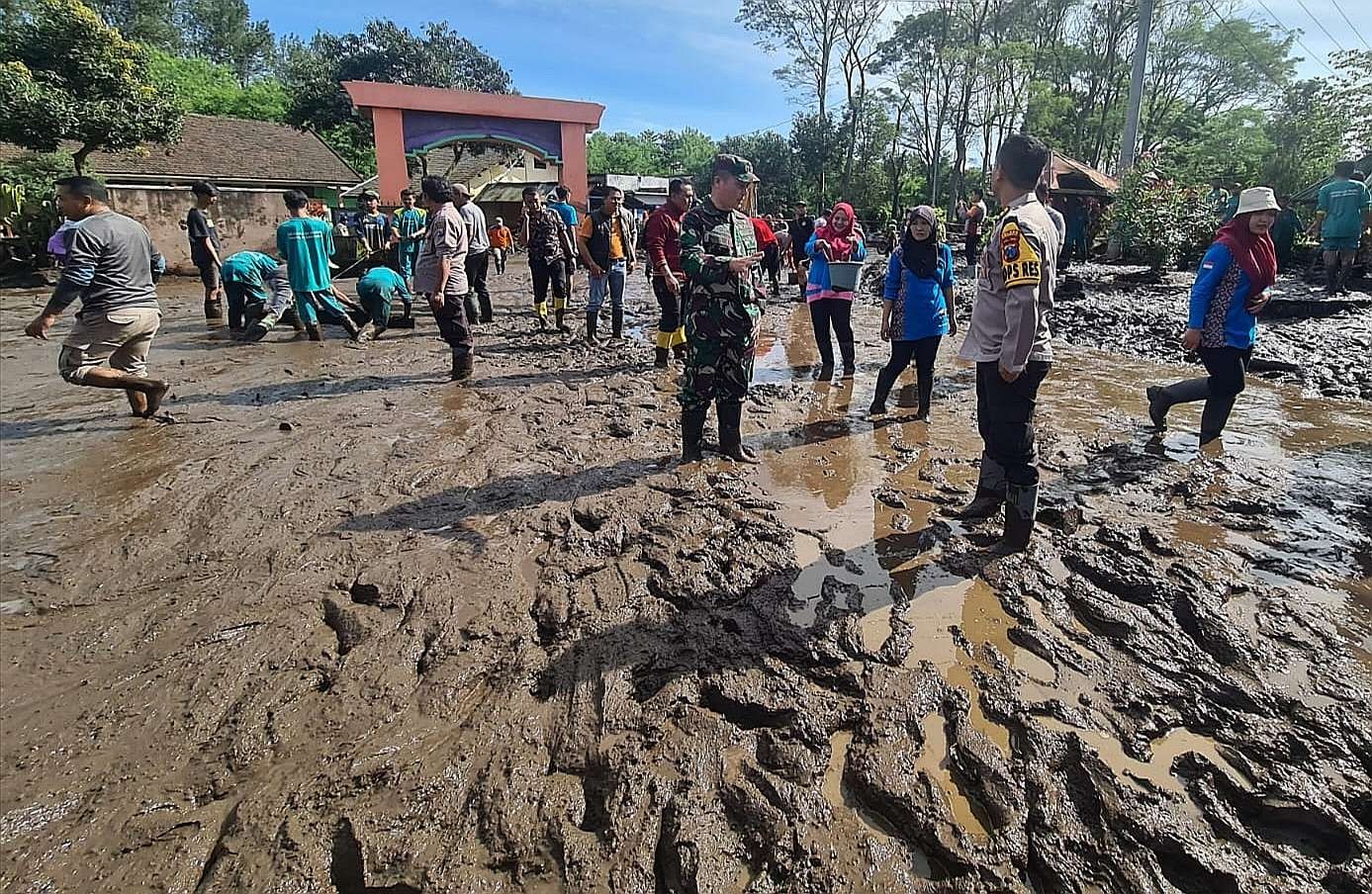 Guru dan siswa bersama anggota TNI, Polri, BPBD, dan relawan kerja bakti membersihkan lumpur memenuhi halaman SDN Sempol 1 Kecamatan Ijen Sempol Bondowoso. (Foto: Guido Saphan/Ngopibareng.id) .