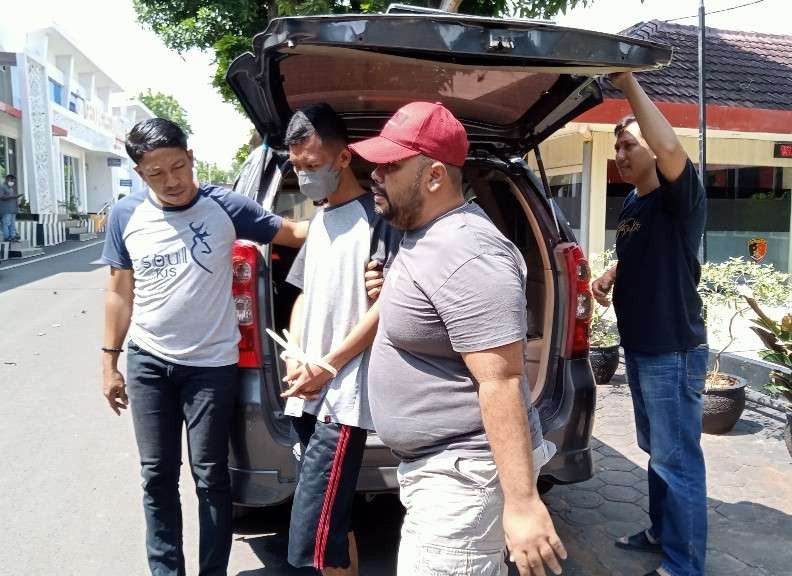 Pelaku pencurian mobil (tangan diborgol) digiring oleh anggota Satreskrim Polres Tuban (Khoirul Huda/Ngopibareng.id)