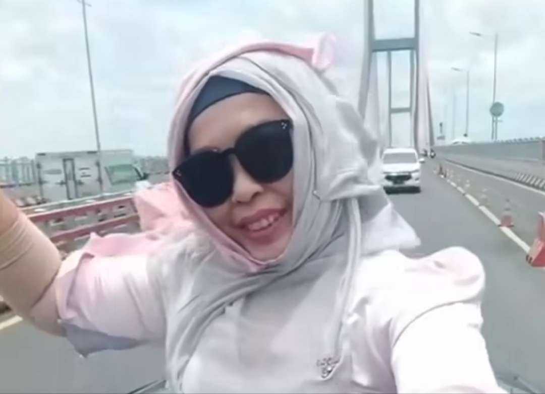 Emak-emak rekam video di sunroof saat melintas Jembatan Suramadu, Surabaya-Madura, Jawa Timur. (Foto: Reels)