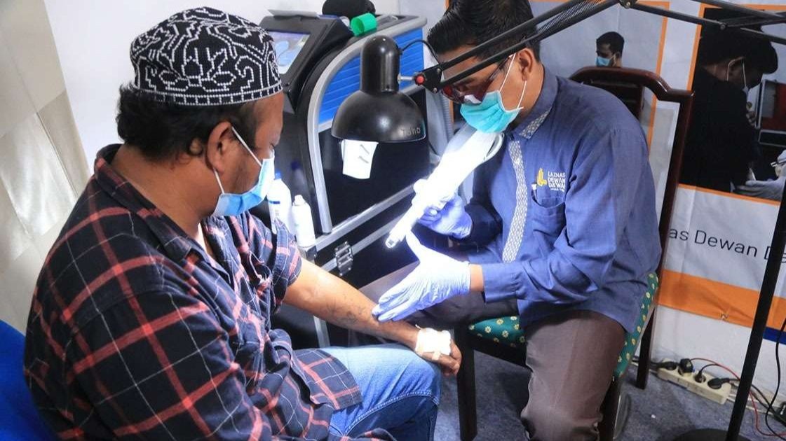 Petugas sedang menghapus tato pada tubuh warga di Rumah Dinas Walikota Probolinggo. (Foto: Ikhsan Mahmudi/Ngopibareng.id)