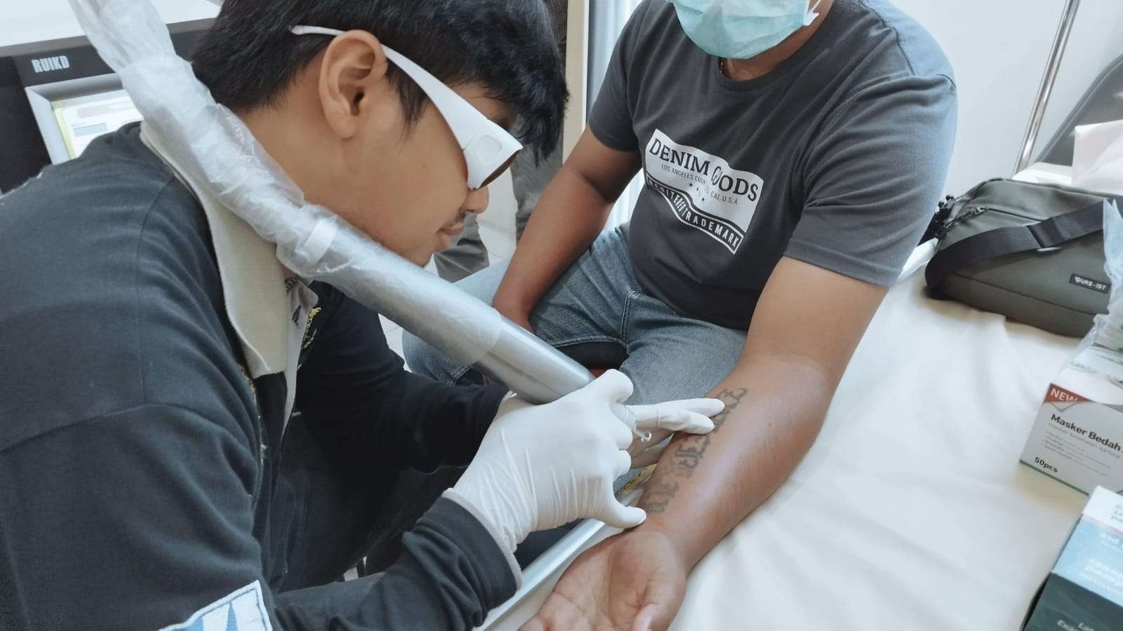 Petugas RS  Bhayangkara sedang menghapus tato seorang pria dalam kegiata Tato Removal Hijrah (foto: Muh Hujaini/Ngopibareng.id)