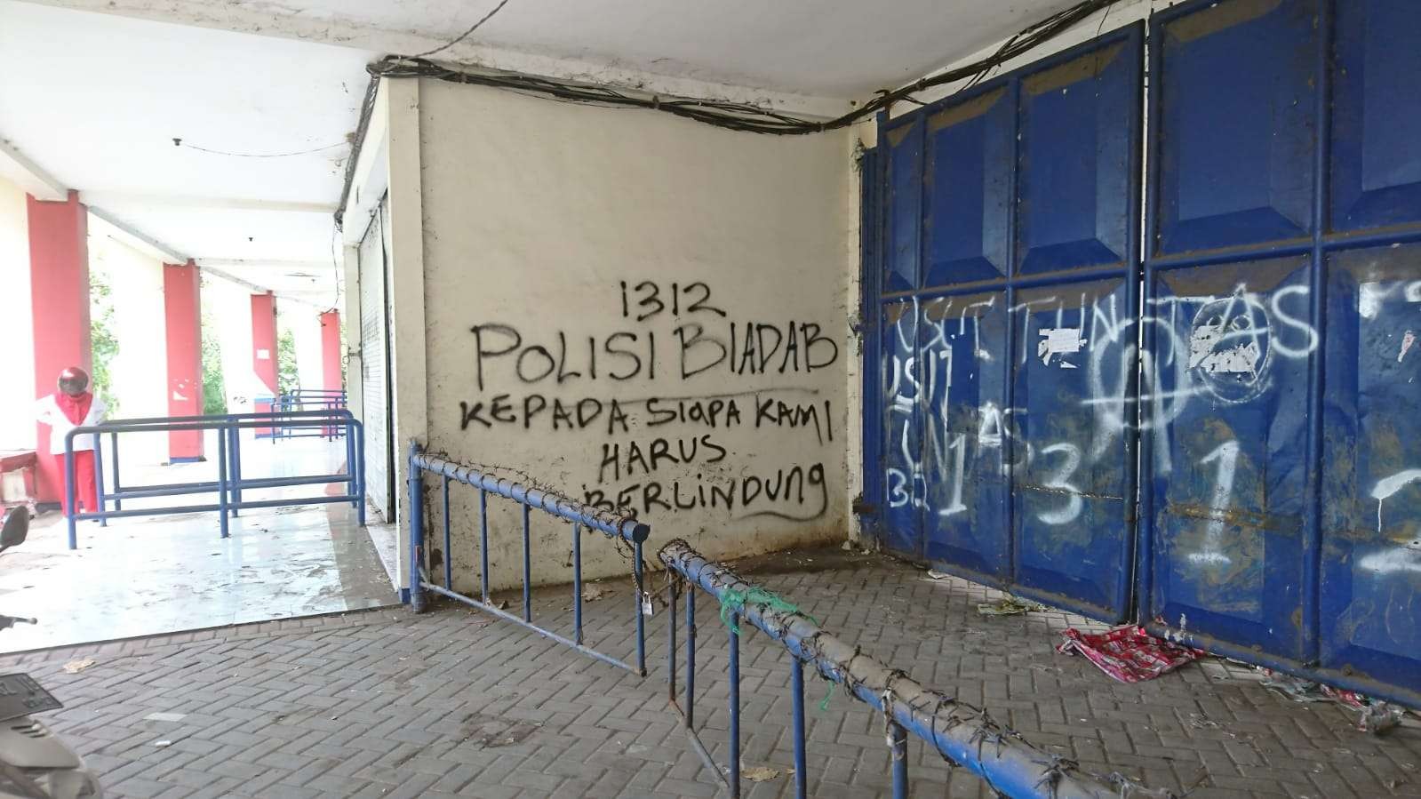 Grafiti bernada protes di gerbang masuk Stadion Kanjuruhan. (Foto: Ngopibareng.id)