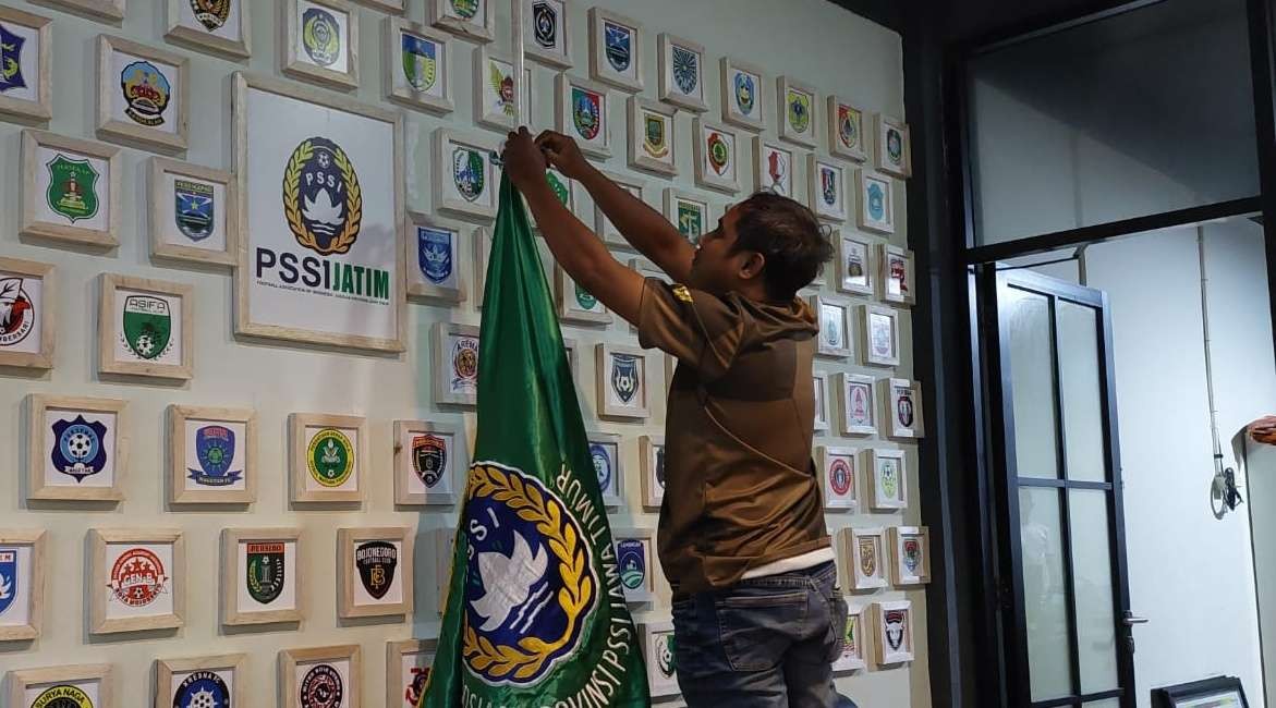 Pegawai Asprov PSSI Jatim memasang bendera setengah tiang. (Foto: Ist)