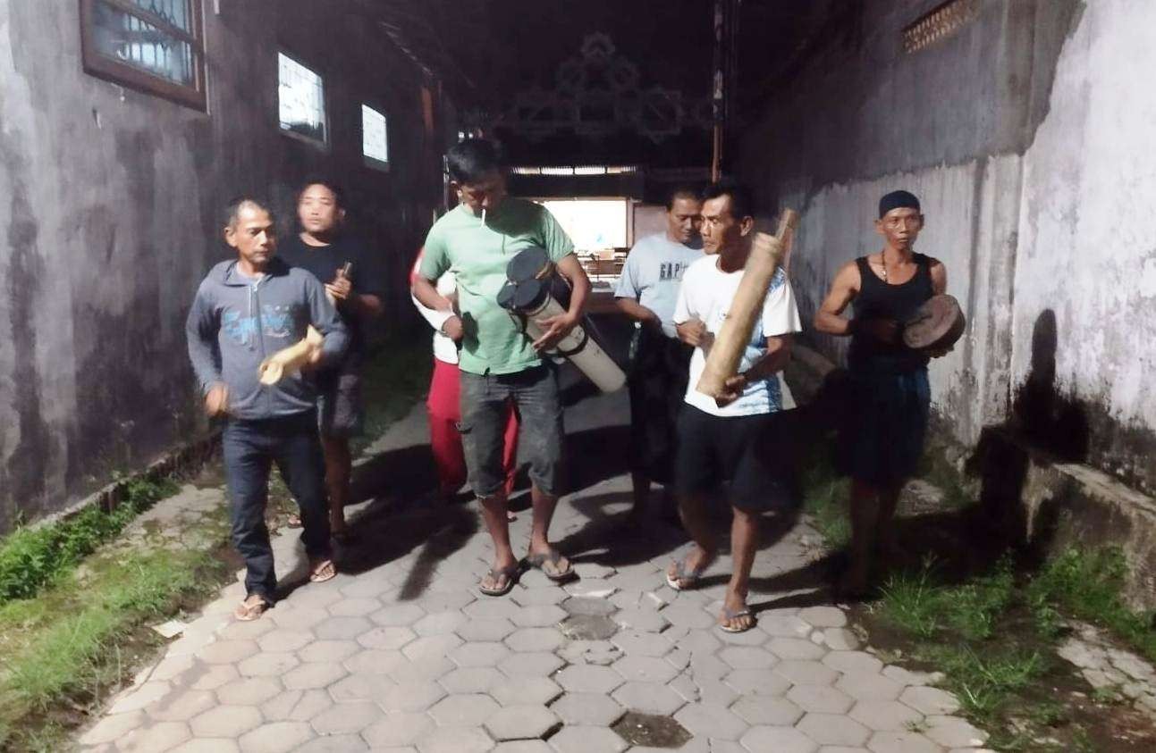 Warga Kampung Loji berkelilng sambil menabuh alat musik patrol sederhana membangunkan warga untuk makan sahur (foto: Muh Hujaini/Ngopibareng.id)