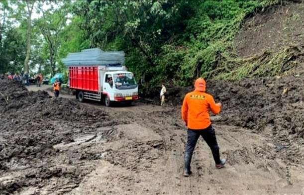 Anggota BPBD Bondowoso memandu truk melewati jalan raya utama Bondowoso menuju kawasan wisata alam Kawah Ijen yang belum sepenuhnya bersih dari material longsor. (Foto: BPBD Bondowoso)