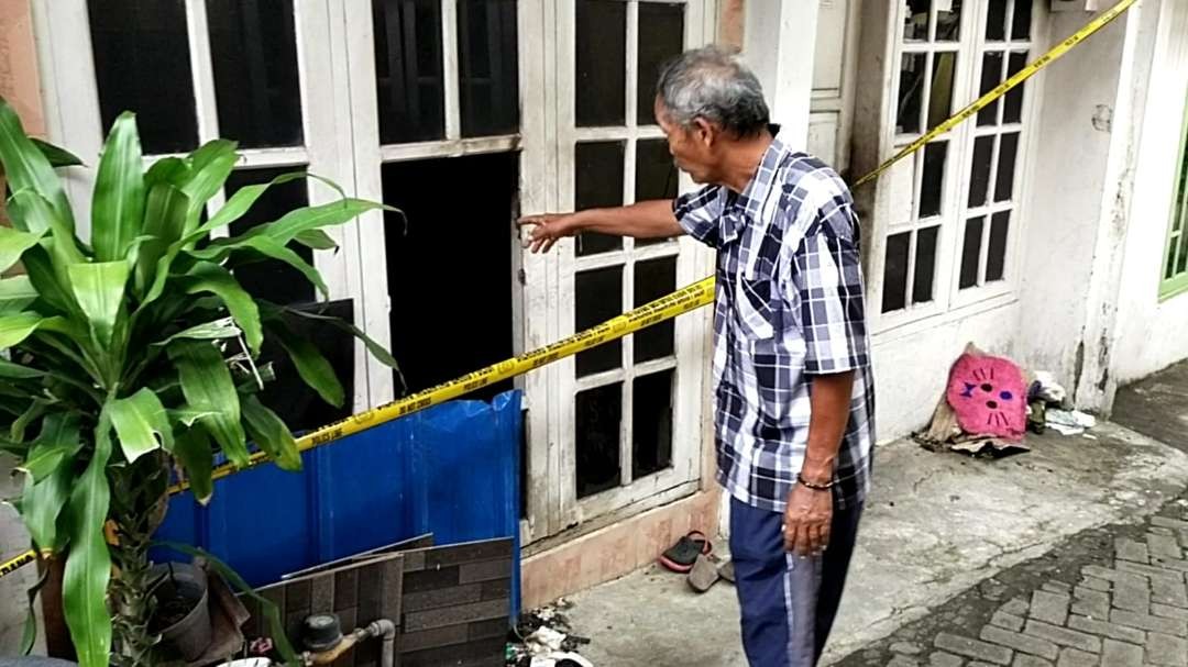 Salah satu saksi menunjukkan jendela kaca yang sempat digunakan untuk kabur oleh anak NN saat dibakar oleh ayah tirinya. (Foto: Rizal A/Ngopibareng.id)