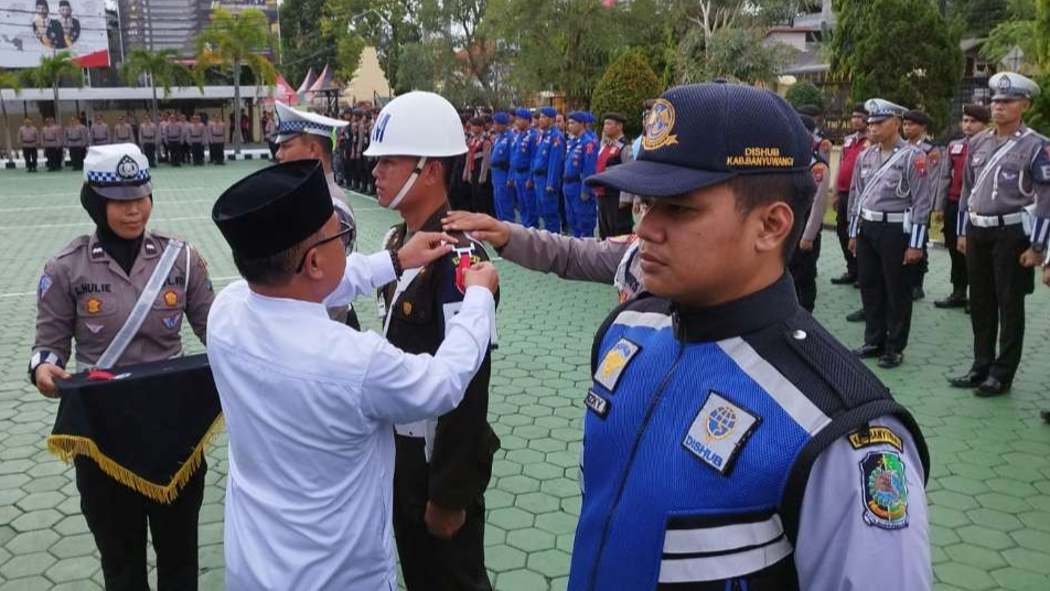 Sekretaris Daerah Banyuwangi, Mujiono memasangkan pita kepada perwakilan petugas yang terlibat dalam operasi ketupat (foto: Muh Hujaini/Ngopibareng.id)