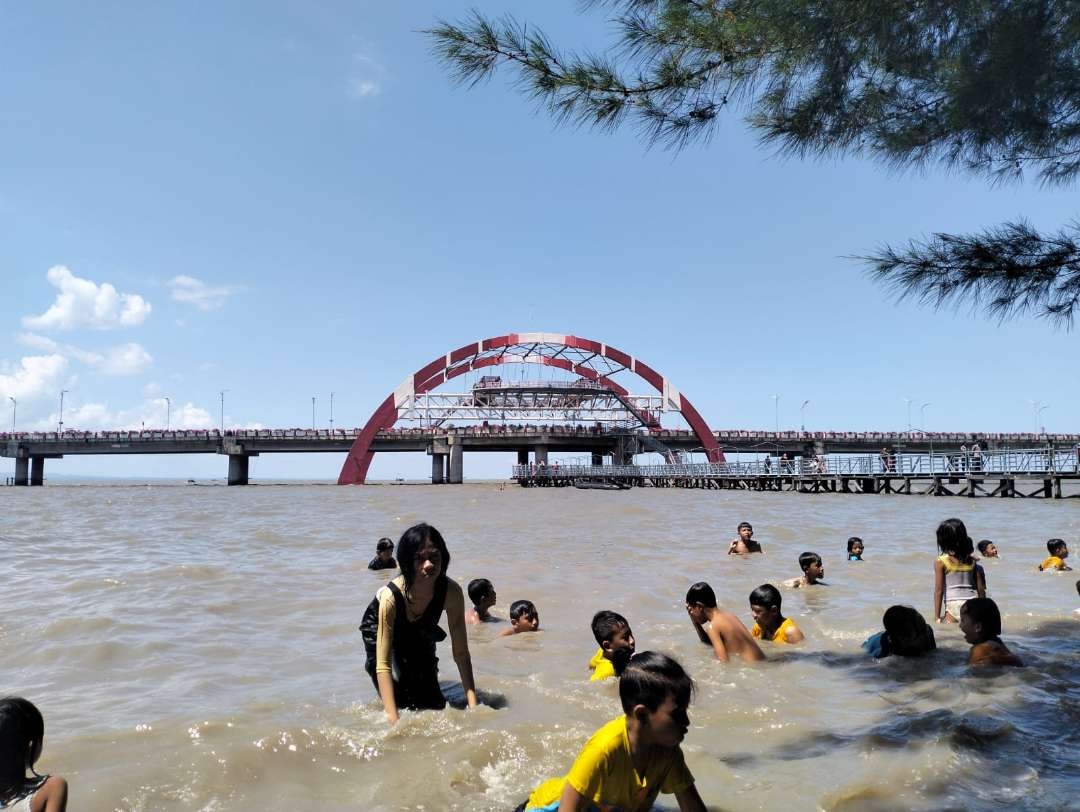 Pengunjung Pantai Kenjeran Surabaya berenang sambil menikmati suasana, Senin 24 April 2023. (Foto: Pita Sari/Ngopibareng.id)