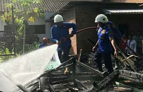 Petugas Damkar Bondowoso memadamkan api menghanguskan rumah warga di Desa Kajar Kecamatan Tenggarang, Senin 1 Mei 2023. (Foto: Guido/Ngopibareng.id)