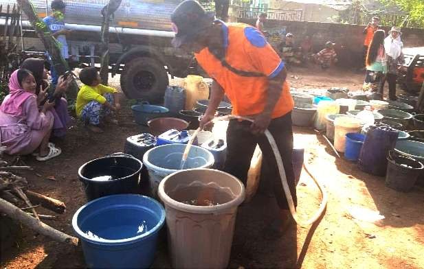 Petugas BPBD Situbondo mengisi air bersih ke timba-timba milik warga Dusun Polay Desa Jatisari Kecamatan Arjasa. (Foto: BPBD Situbondo)
