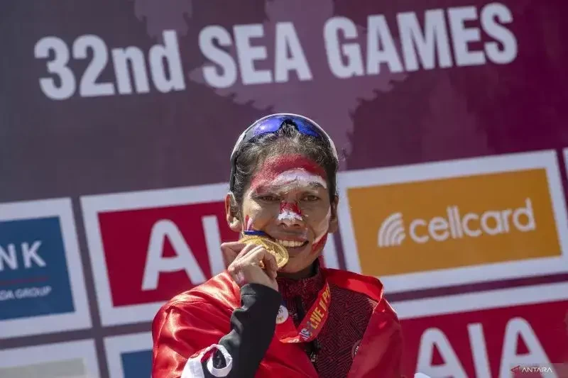 Pelari putri Indonesia Odekta Elvina Naibaho mengigit medali emas saat penyerahan medali marathon SEA Games 2023 di kawasan situs warisan budaya dunia UNESCO Angkor Wat, Siem Reap, Kamboja. (Foto: Ant)