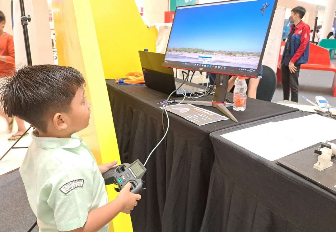 Salah satu pengunjung, Daffa saat mencoba simulator menerbangkan pesawat di both Robotika ITS dalam acara Pasar Urban. (Foto: Pita Sari/Ngopibareng.id)