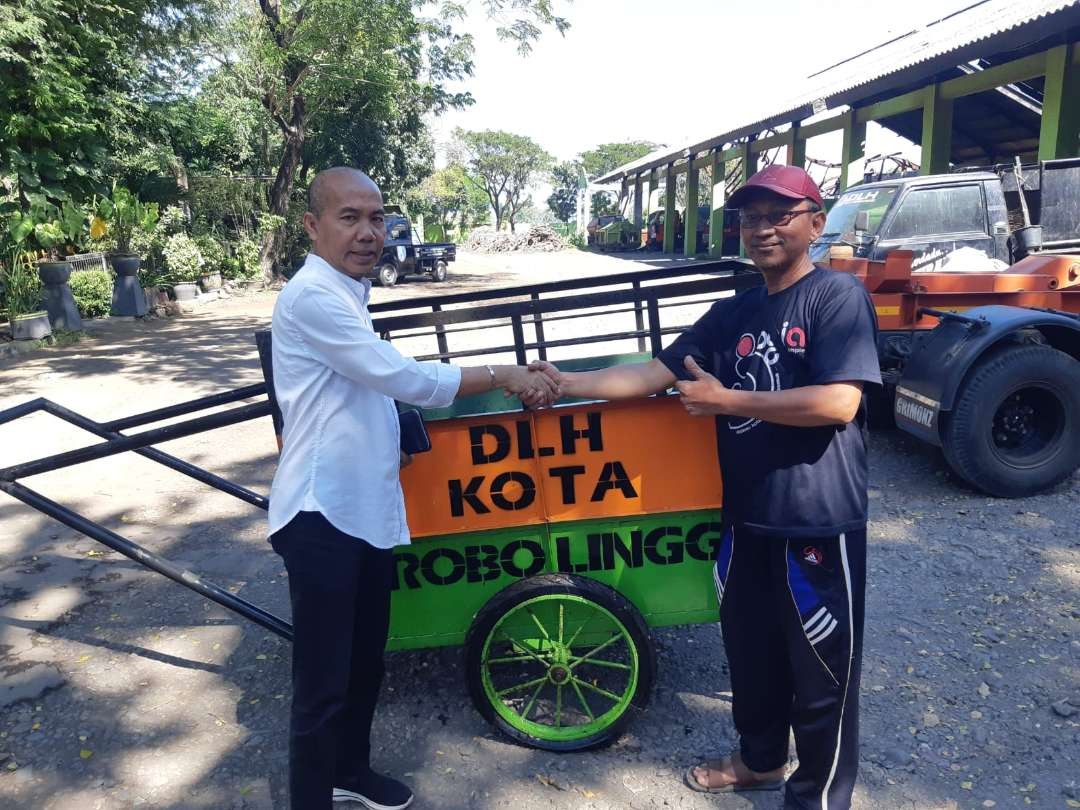 Kepala DLH, Rachmadeta Antariksa (kiri) menyerahkan gerobak baru untuk pengganti gerobak sampah yang hilang dicuri di Kelurahan/Kecamatan Kanigaran. (Foto: Ikhsan Mahmudi/Ngopibareng.id)