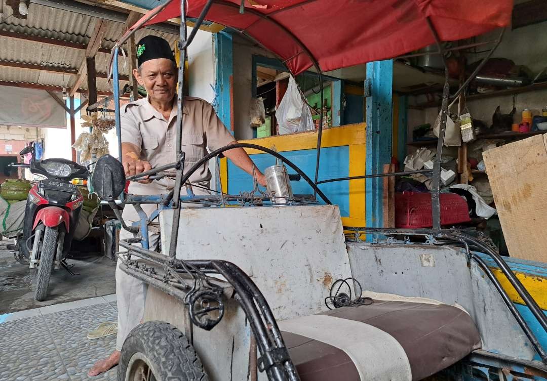 Muhammad Mudjib saat memperlihatkan becak yang dikayuh sejak 30 tahun lebih lalu. Kini, becak tersebut masih terpajang di teras rumahnya. (Foto: Pita Sari/Ngopibareng.id)