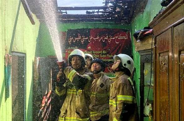 Petugas Damkar Bondowoso memadamkan api membakar dua rumah warga di Desa Maskuning Kulon Kecamatan Pujer. (Foto: Satpol PP Damkar Bondowoso)