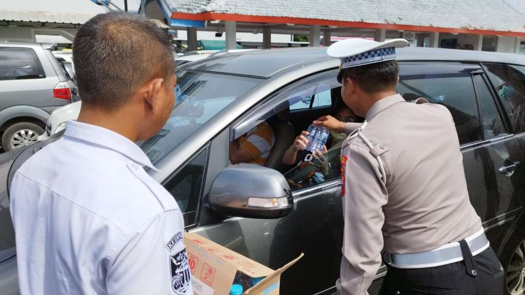 Kasat Lantas Polresta Banyuwangi Kompol Randy Asdar membagikan air minum kepada pengendara yang terjebak macet (foto: Muh Hujaini/Ngopibareng.id)