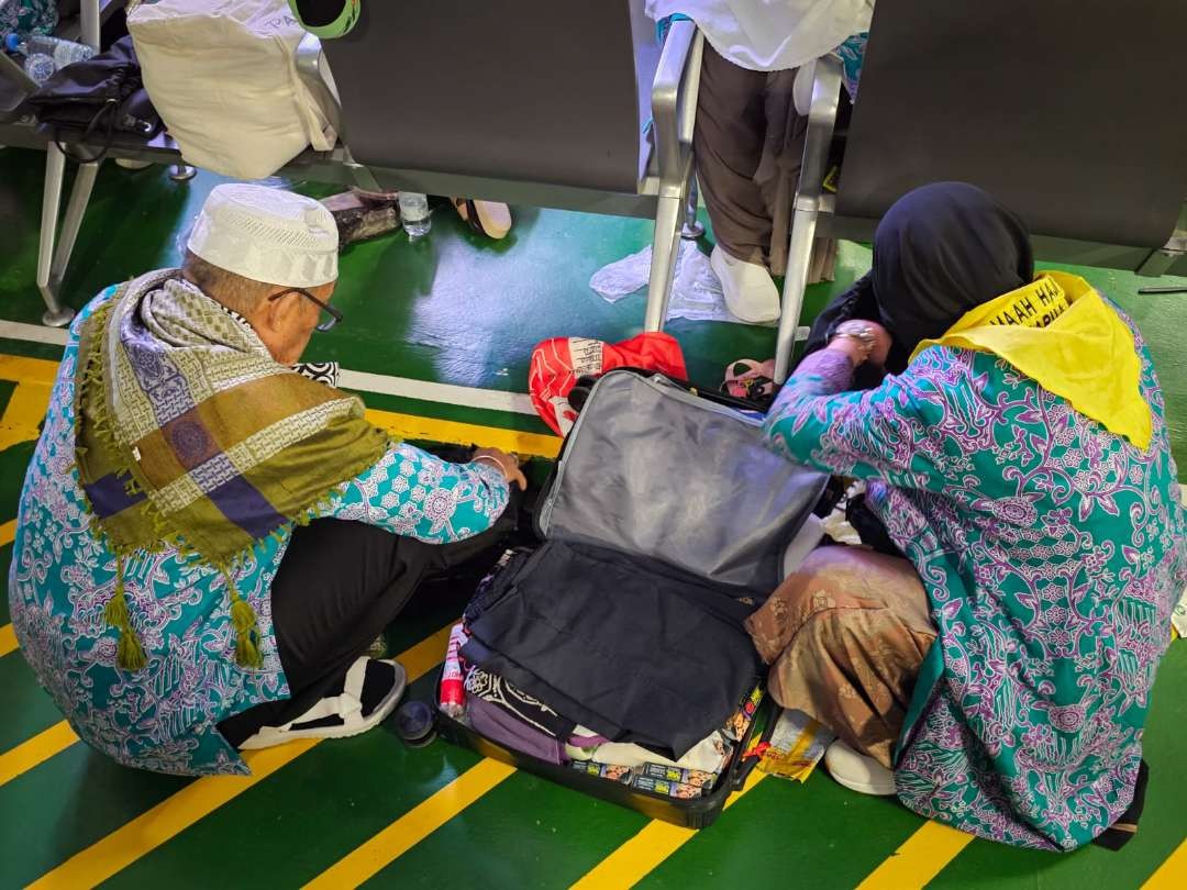 Jemaah haji yang kopernya melebihi kapasitas atau membawa benda-benda yang dilarang sibuk membongkar barang. (Foto: Witanto/Ngopibareng.id)