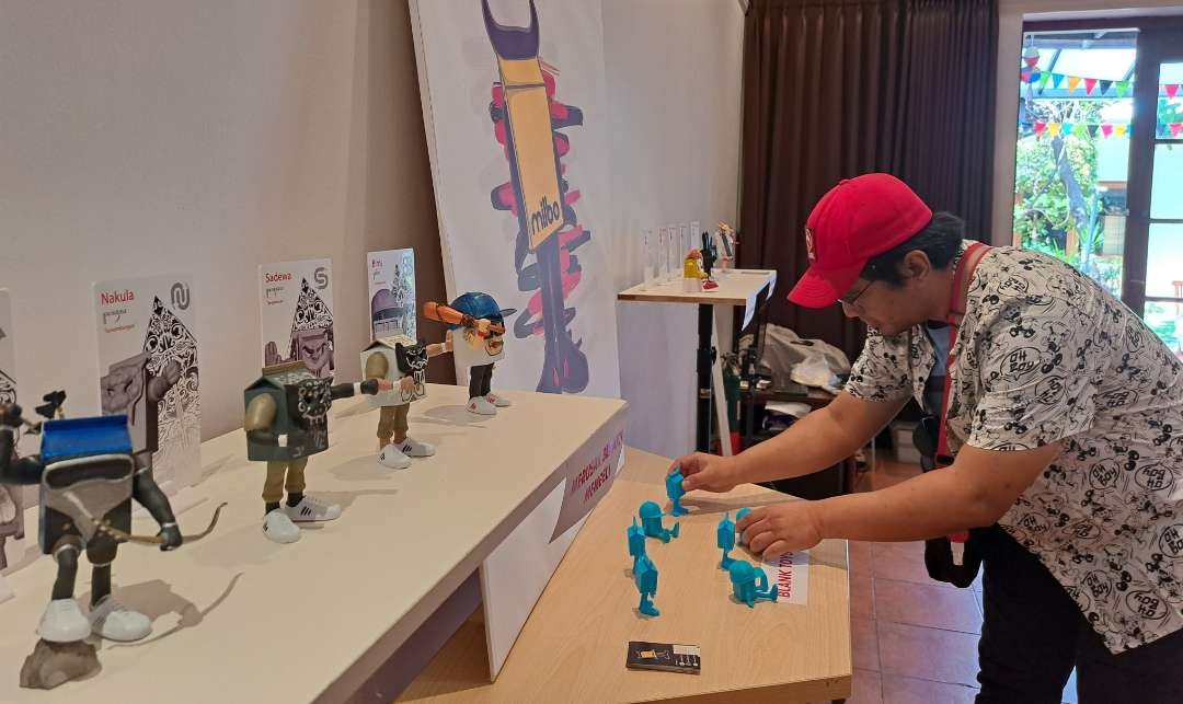 Salah satu seniman toys asal Surabaya, Rifki yang sedang menunjukan karyanya bernam Milbo toys yang dipamerkan di Wisma Jerman. (Foto: Pita Sari/Ngopibareng.id)