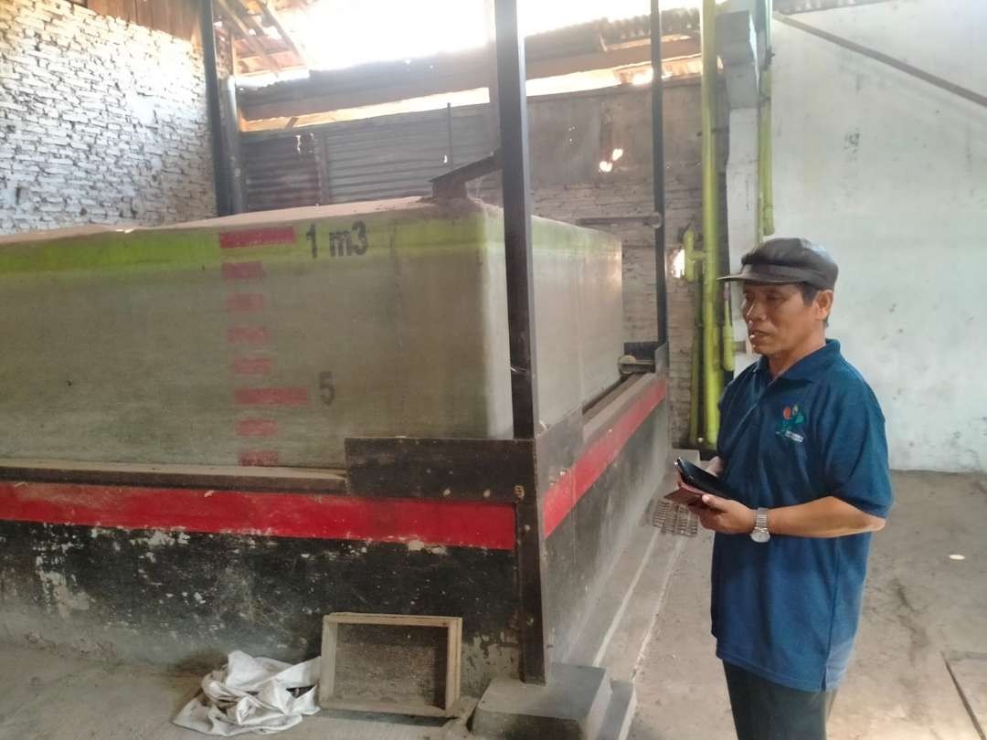 Mahfud Sidik menunjukkan instalasi pengolahan limbah cair pabrik tahu menjadi biogas. (Foto: Ikhsan Mahmudi/Ngopibareng.id)