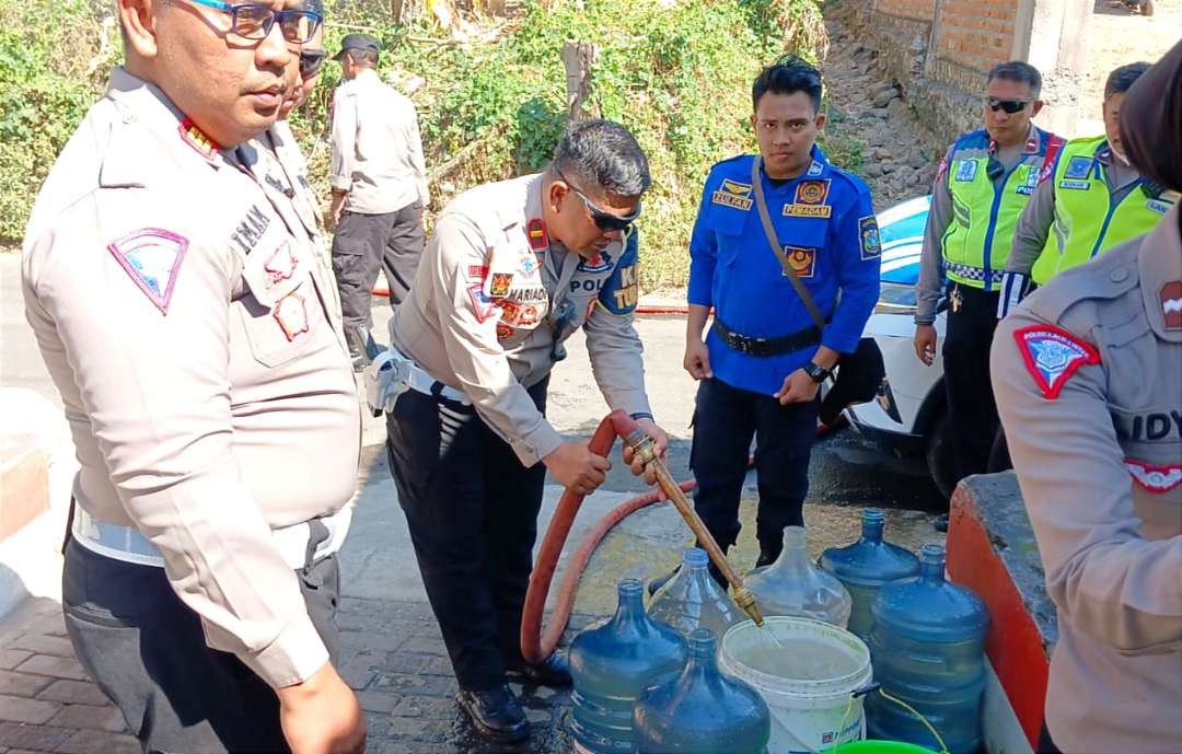 Anggota Polres Bondowoso terjun mendistribusikan air bersih ke desa mulai kekurangan air bersih, Kamis 3 Agustus 2023.(Foto: Guido/Ngopibareng.id)