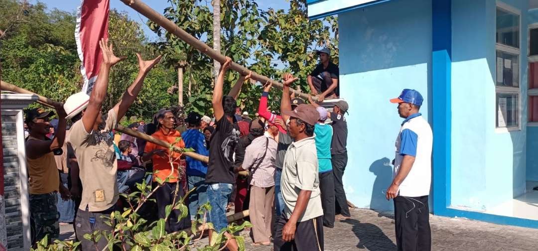 Warga bersama-sama membuka segel yang terpasang selama 19 hari di pintu masuk Kantor Desa Mundurejo, Jember, Jawa Timur. (Foto: Istimewa)