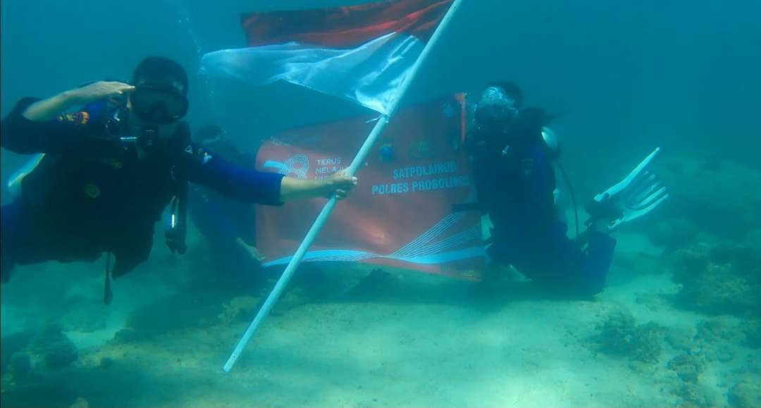 Personel Satpolairud mengibarkan Bendera Merah Putih di bawah perairan laut Pulau Giliketapang. (Foto: Polairud).