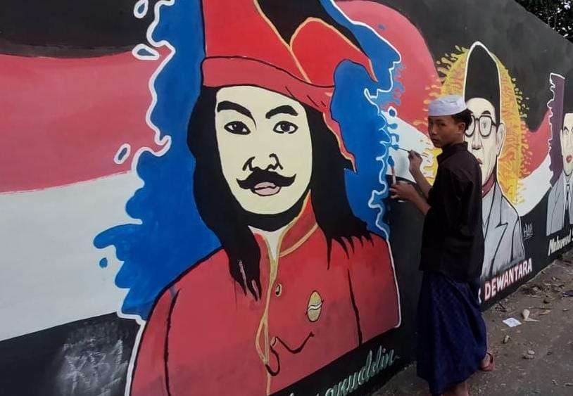 Seorang santri sedang melukis mural sosok pahlawan nasional di dinding. (Foto: Ikhsan Mahmudi/Ngopibareng.id)