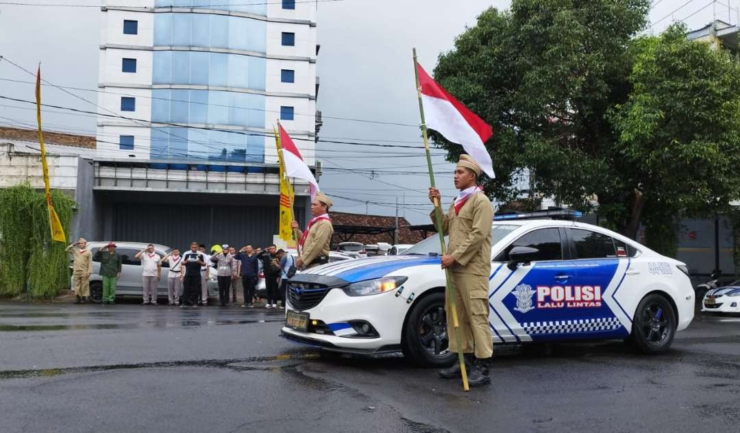 Dua petugas berpakaian veteran membawa bendera di tengah simpang lima (Foto: Muh Hujaini/Ngopibareng.id)