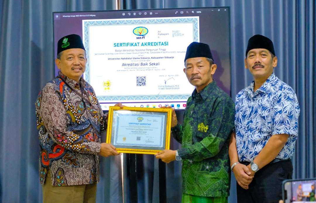 Rektor Unusidaz Fatkhul Anam menyerahkan Piagam Akreditasi Baik Sekali kepada Ketua PCNU Sidoarjo, KH Zainal Abidin. (Foto: Aini Arifin/Ngopibareng.id)