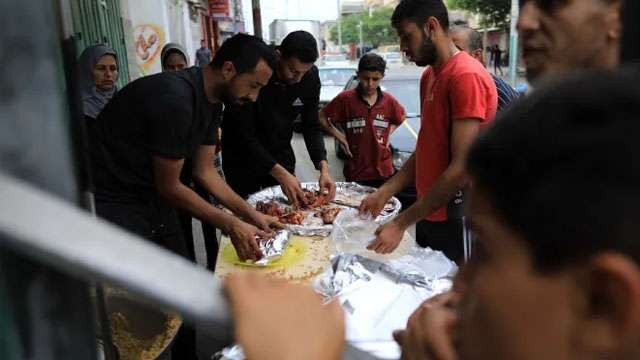 Keluarga Abu Assi memasak makanan untuk para pengungsi Khan Younis di Jalur Gaza yang terus menerus diborbardir tentara zionis Israel. [Yaser Qudeih/Al Jazeera]