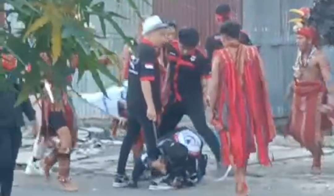 Sebuah video beredar di media sosial. Terlihat seorang meraung kesakitan, diinjak-injak sekelompok orang memakai baju dengan rumbai-rumbai warna merah. Insiden terjadi di Kota Bitung, Sulawesi Utara. (Foto: tangkapan video)