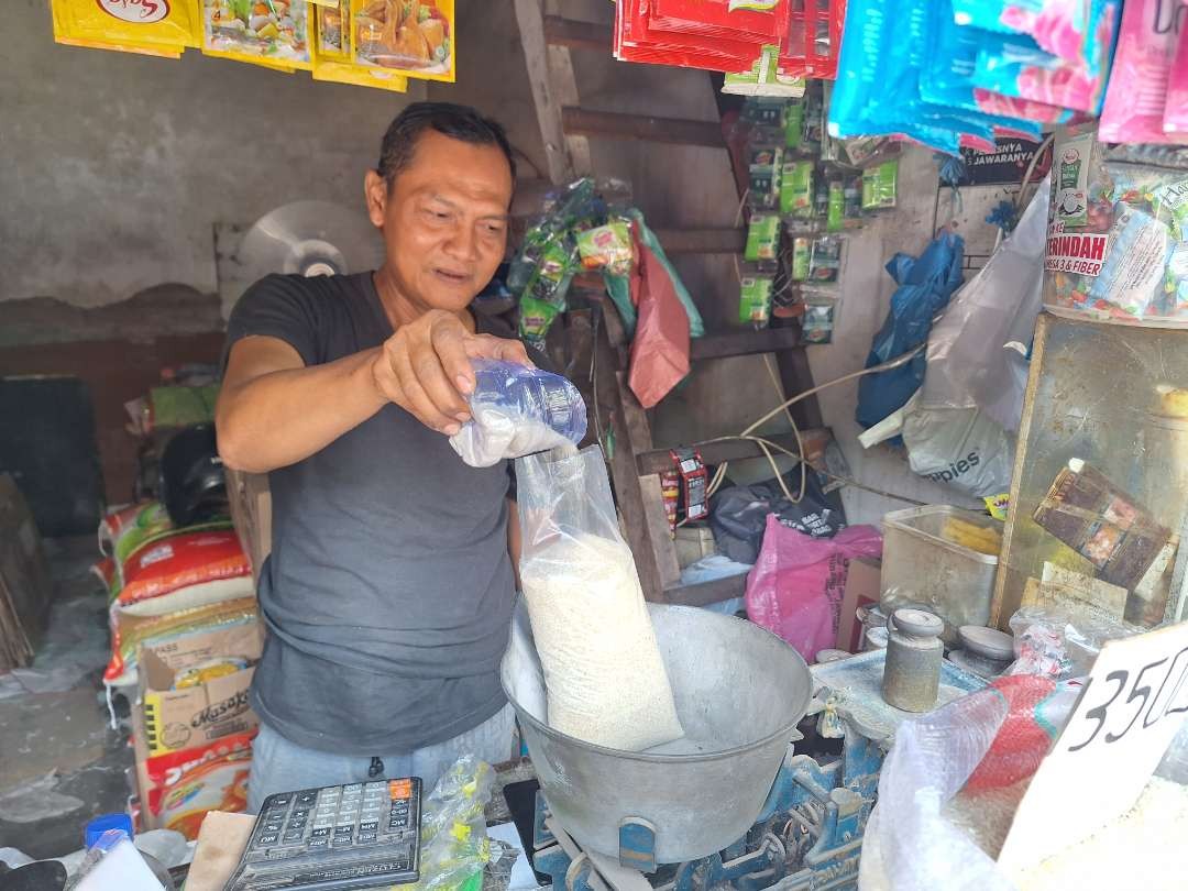 Romaji, salah satu pedagang di Pasar Pucang Anom Surabaya, sedang menimbang gula dagangannya. (Foto: Julianus Palermo/Ngopibareng.id)