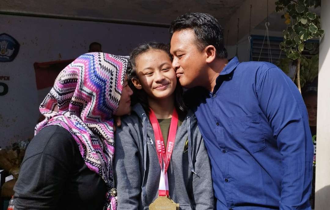 Dhea dicium oleh ayah ibunya saat tiba di sekolahnya (foto:Muh Hujaini/Ngopibareng.id)