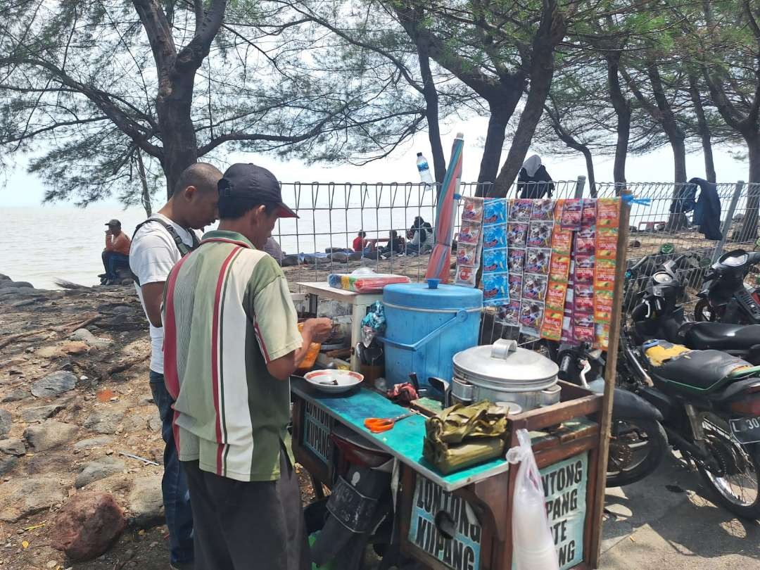 Mashuri saat melayani pembeli yang membeli lontong kupang di kawasan Watu-Watu, Pantai Kenjeran, Surabaya. (Foto: Julianus Palermo/Ngopibareng.id)