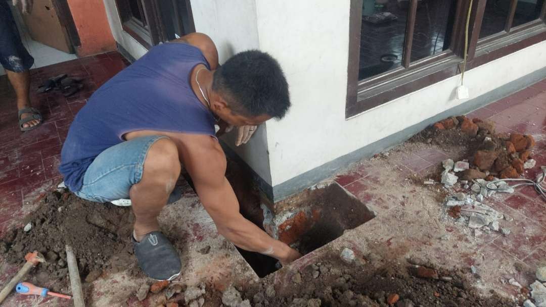 Nur Anta Maulana, pemilik rumah di Jalan Flamboyan Gang I, Kota Probolinggo menggali teras rumahnya mengeluarkan hawa panas. (Foto: Ikhsan Mahmudi/Ngopibareng.id)