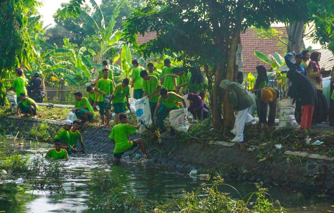 Belasan siswa YPM Sepanjang melakukan kerja bakti bersihkan sungai (Foto: Aini/Ngopibareng.id)