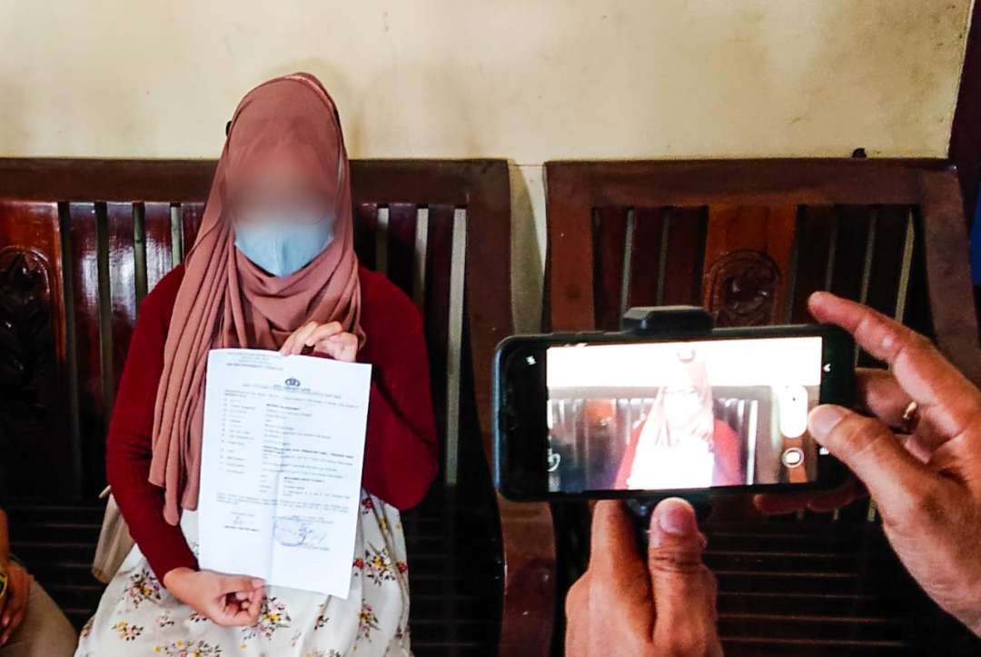 Ibu korban saat menunjukkan surat laporan kepolisian. (Foto: Aini Arifin/Ngopibareng.id)