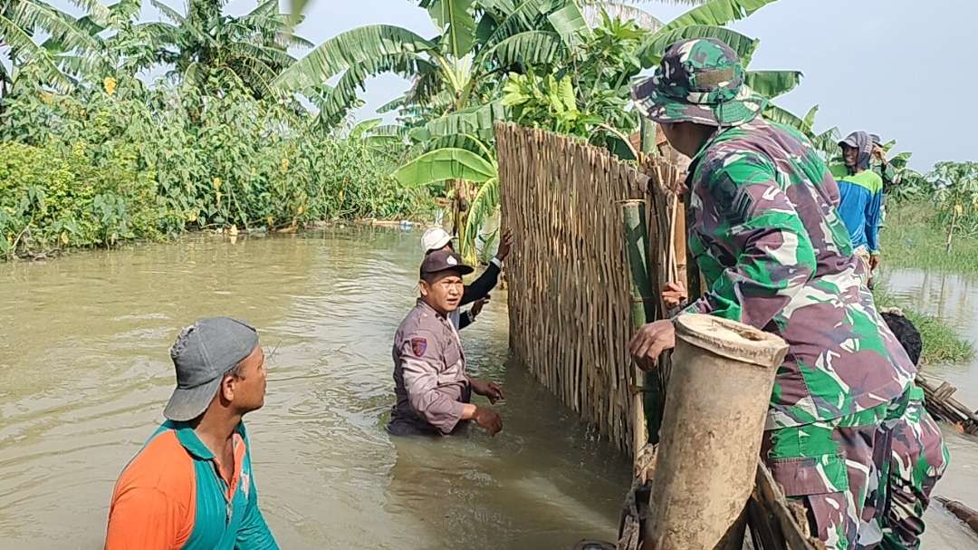 Anggota Koramil Modo, polsek setempat bersama masyarakat dan BPBD sedang memperbaiki tanggul Sungai Dusun Kepoh, Desa Kacangan, Kecamatan Modo, yang jebol. (Foto: Istimewa)