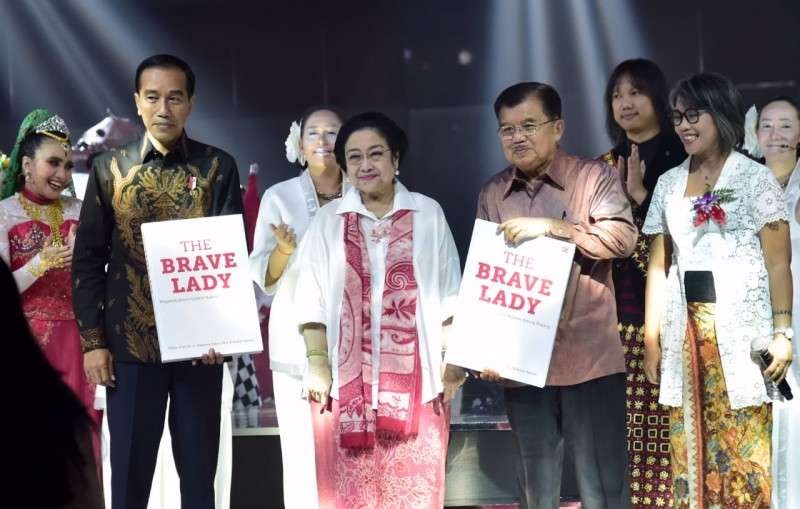 Presiden Joko Widodo dan Wakil Presiden Juduf Kalla, memperlihatkan hadiah buku biografi Megawati. ( Foto: setpres for ngopibareng.id)).
