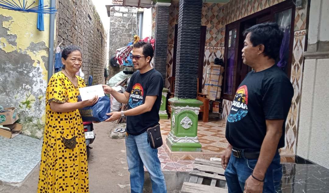 Ketua Pokdarwis Pantai Kelapa Tuban menyerahkan bantuan sembako dan uang tunai kepada warga (Khoirul Huda/Ngopibareng.id)