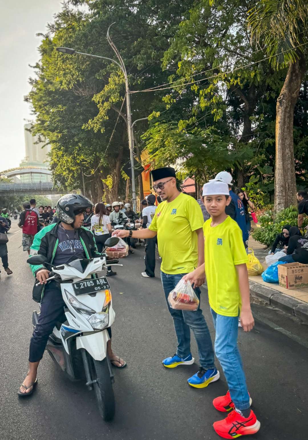 Alfadistian dan anaknya Azlan membagikan takjil dalam acara Charity Night Run yang digagas oleh Coffee Ride (/Run) Society Surabaya. (Foto: Istimewa)