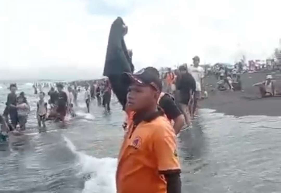 Relawan BPBD Jember saat memamerkan kantong jenazah kepada pengunjung Pantai Paseban yang mandi di laut. (Foto: Istimewa)