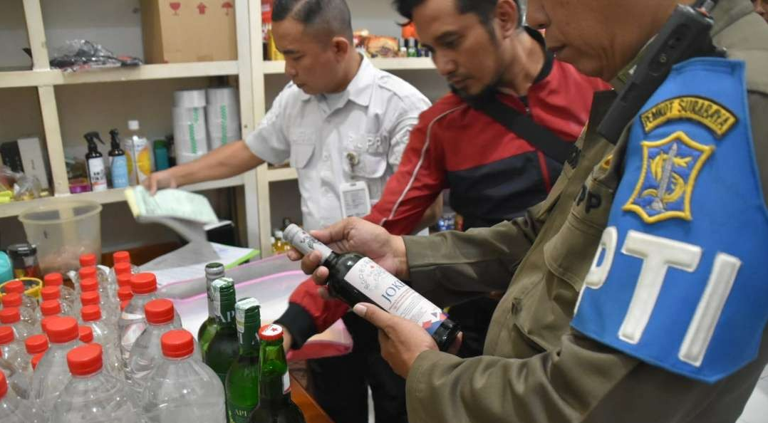 Petugas Satpol PP Kota Surabaya saat menyita puluhan botol minuman beralkohol, di sebuah toko kelontong di Jalan Gubeng Kertajaya, Surabaya. (Foto: Humas Pemkot Surabaya)